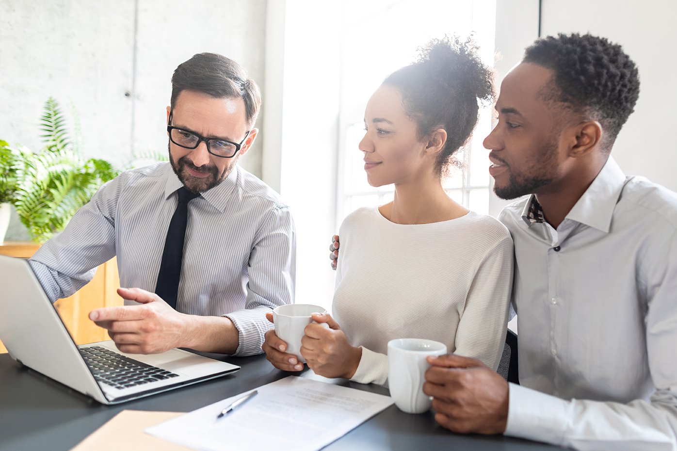 young-couple-meeting-with-an-advisor-looking-at-a-computer-while-drinking-coffee