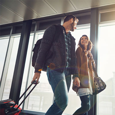 young-couple-traveling-walking-with-suitcases-and-smiling-400x400